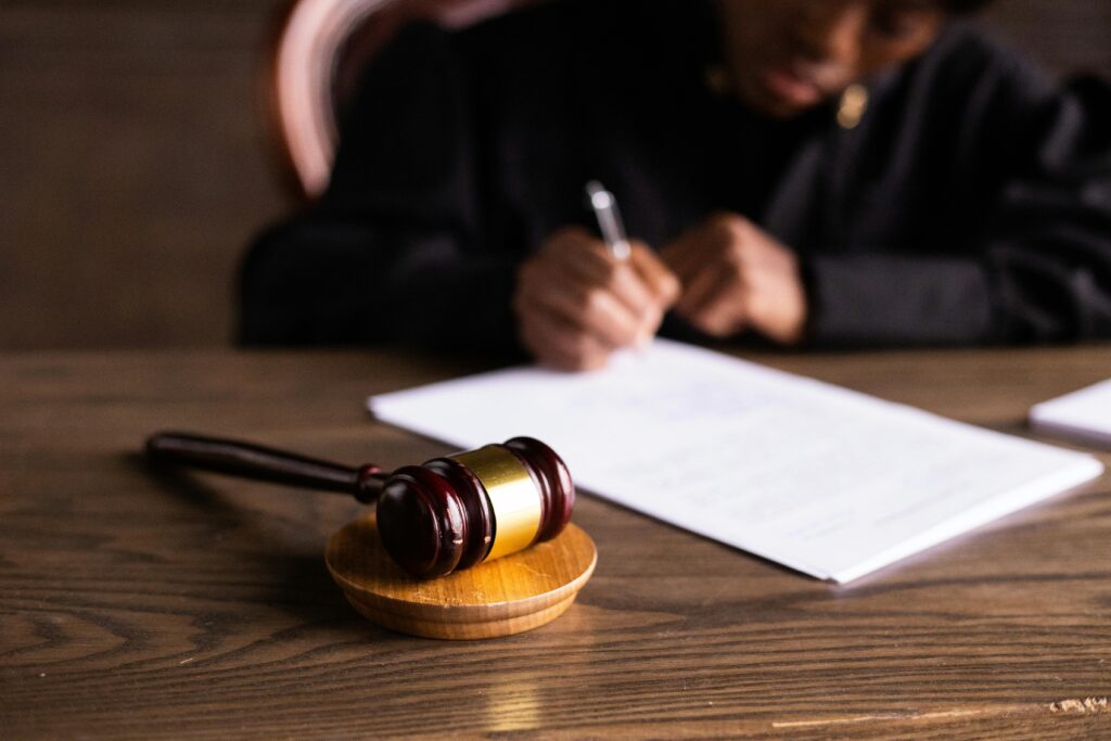 A judge writes on a piece of paper with a gavel in the foreground